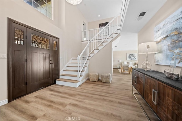 foyer with light hardwood / wood-style floors and a towering ceiling