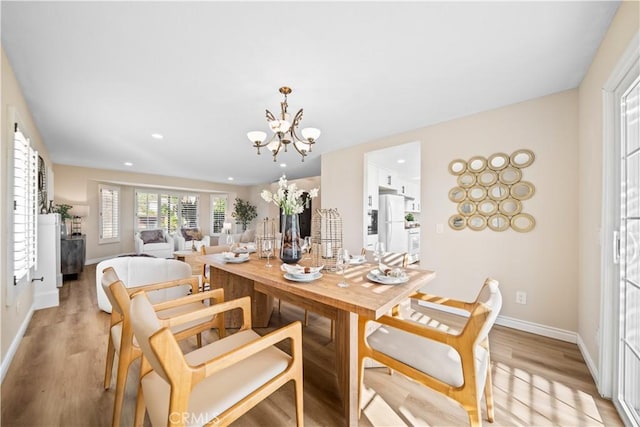 dining space with light wood-type flooring and an inviting chandelier