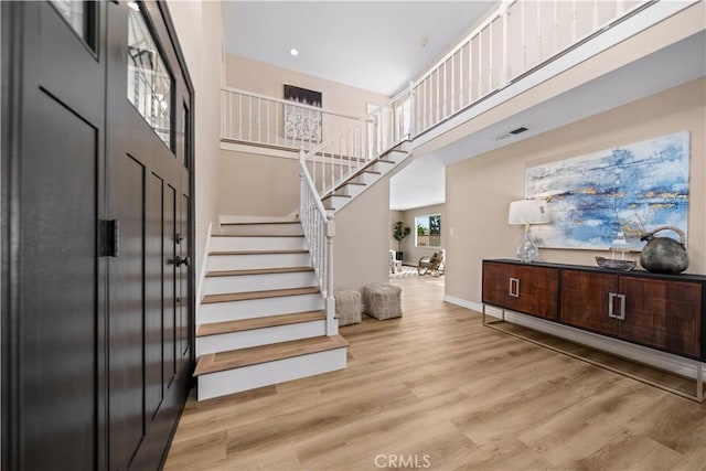 entrance foyer featuring a towering ceiling and light wood-type flooring