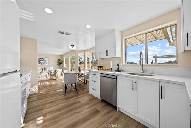 kitchen featuring white fridge, light hardwood / wood-style floors, stainless steel dishwasher, white cabinets, and sink