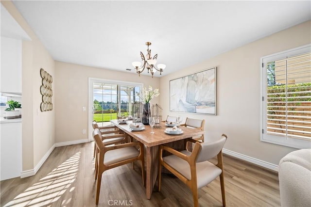 dining area with light wood-type flooring and a chandelier