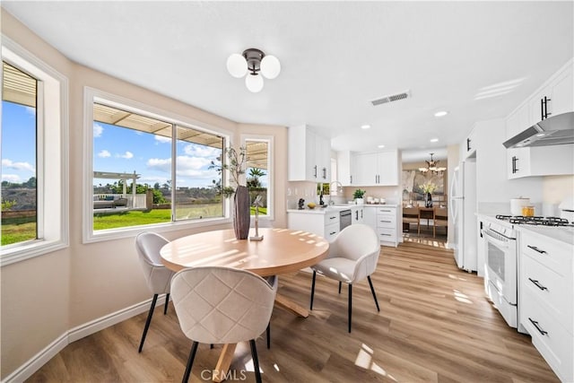 dining room with light wood-type flooring, a notable chandelier, and sink