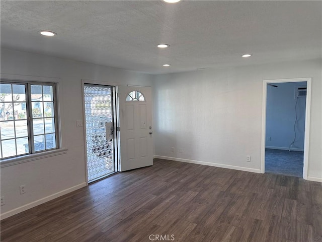 foyer entrance featuring dark hardwood / wood-style floors, a textured ceiling, and a wall mounted air conditioner