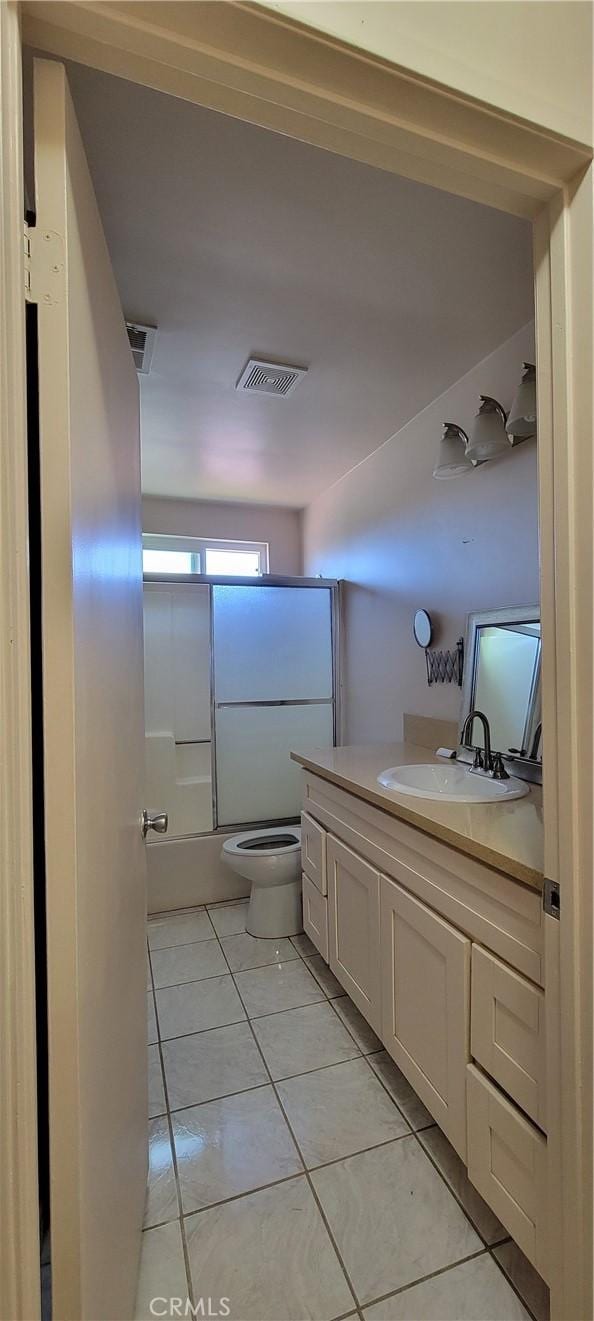 full bathroom with toilet, tile patterned flooring, vanity, and shower / bath combination with glass door