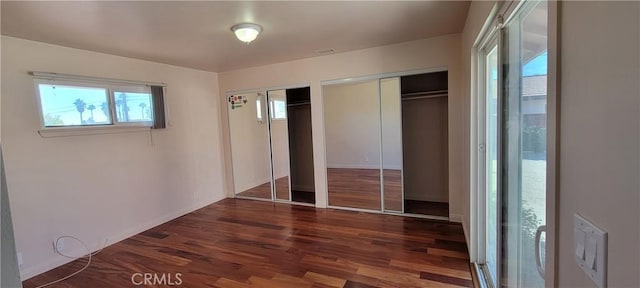 unfurnished bedroom with multiple closets and dark hardwood / wood-style flooring