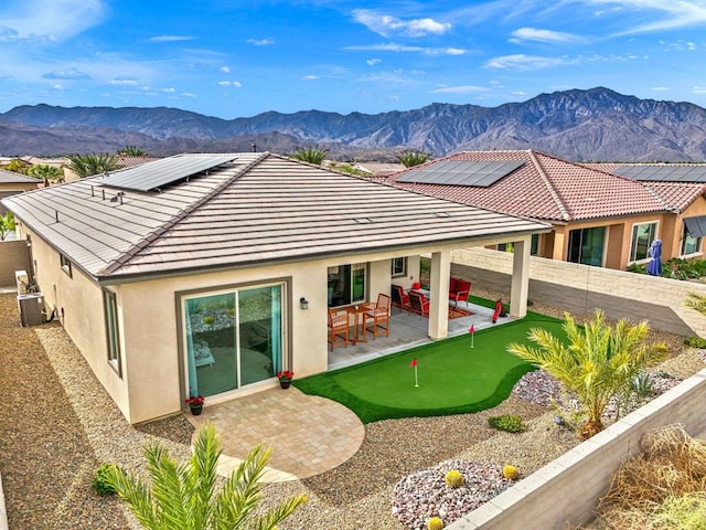 rear view of property featuring a mountain view, a patio area, cooling unit, and solar panels