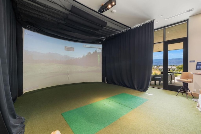 recreation room with carpet, expansive windows, a mountain view, and golf simulator