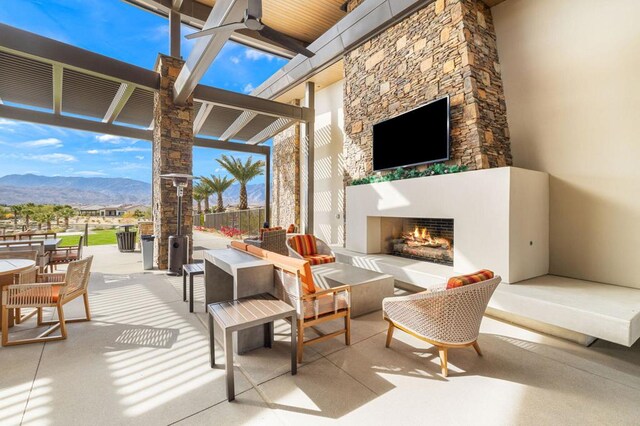 view of patio with a mountain view and an outdoor living space with a fireplace