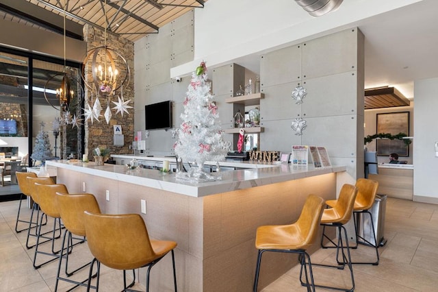 bar with light tile patterned floors, an inviting chandelier, and a high ceiling