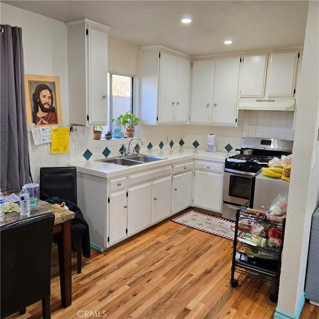 kitchen featuring light wood-type flooring, sink, white cabinets, and stainless steel gas range oven