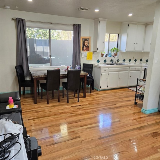 kitchen featuring light hardwood / wood-style flooring, white cabinets, tasteful backsplash, and sink