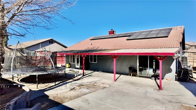 back of house with a patio area and a trampoline