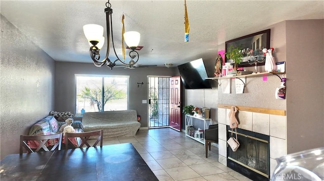 living room with a textured ceiling, a tile fireplace, and a chandelier