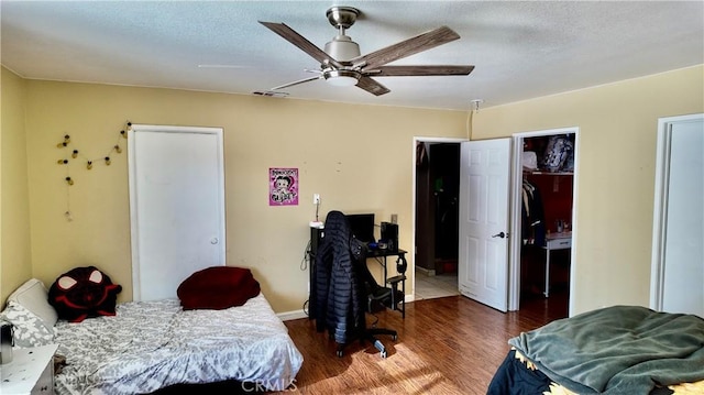 bedroom with dark wood-type flooring, ceiling fan, a textured ceiling, and a spacious closet