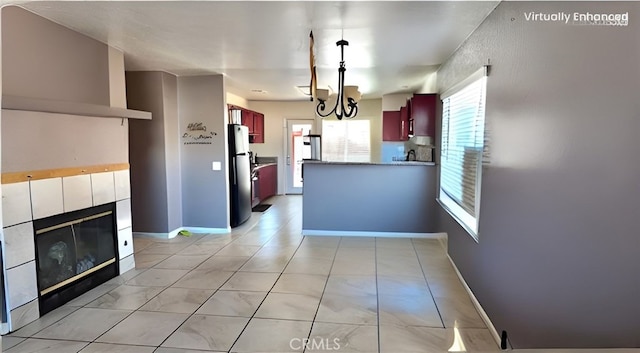 11807 Lupin Rd, Adelanto, CA 92301 - kitchen with freestanding refrigerator, reddish brown cabinets, a peninsula, a chandelier, and a tile fireplace