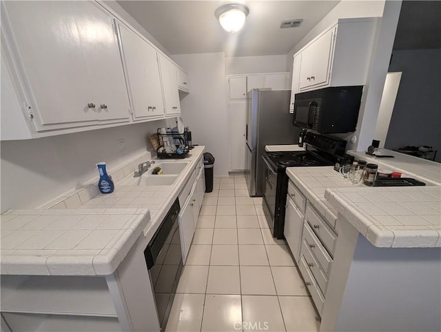 kitchen with black appliances, white cabinets, kitchen peninsula, and tile counters