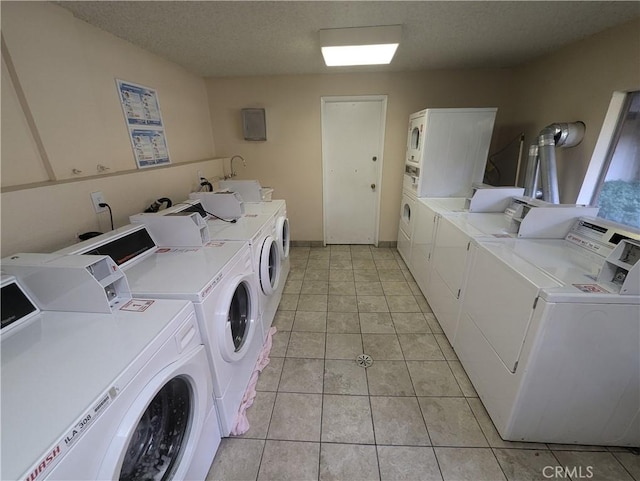 laundry area with a textured ceiling, light tile patterned floors, and washer and dryer