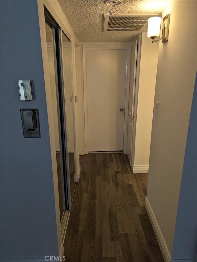 hall featuring a textured ceiling and dark hardwood / wood-style floors