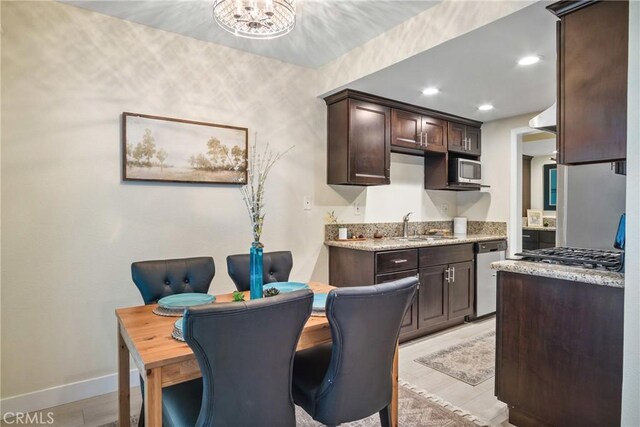 kitchen featuring light stone counters, sink, dark brown cabinetry, and stainless steel appliances