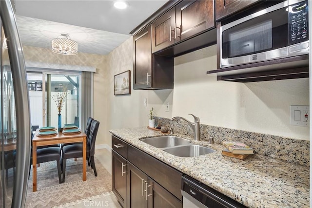 kitchen featuring dark brown cabinets, sink, light stone counters, and stainless steel appliances