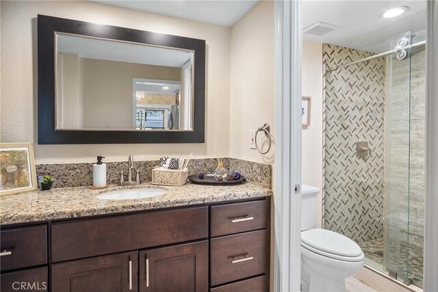 bathroom featuring toilet, walk in shower, and vanity