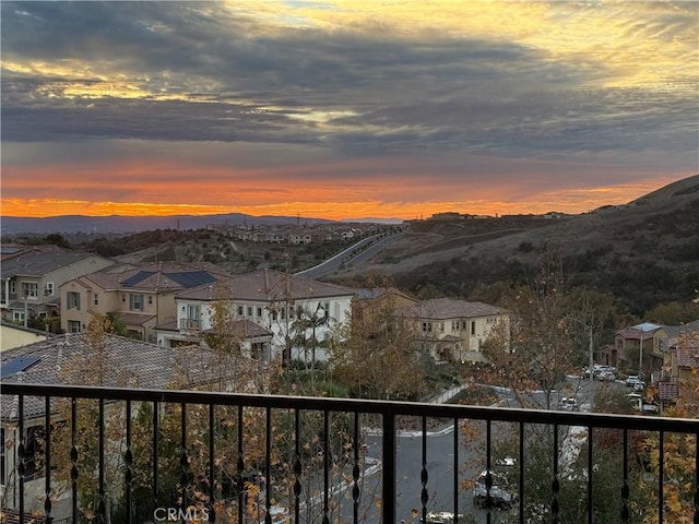 balcony at dusk featuring a residential view and a mountain view