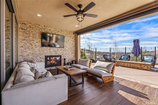 view of patio with an outdoor living space with a fireplace and ceiling fan