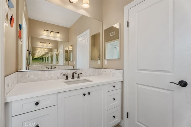 bathroom with visible vents, vanity, and decorative backsplash