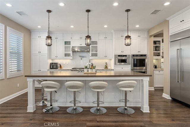 kitchen featuring pendant lighting, white cabinets, stainless steel appliances, and a large island with sink