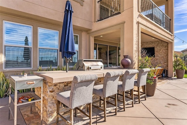 view of patio / terrace with a balcony, a grill, an outdoor kitchen, and outdoor wet bar