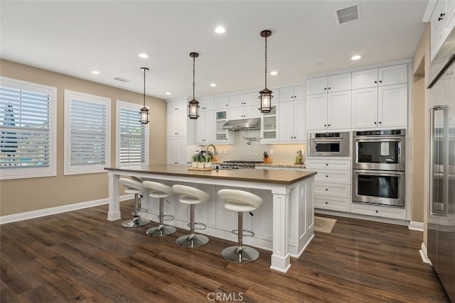 kitchen featuring a center island, a breakfast bar area, white cabinets, and double oven