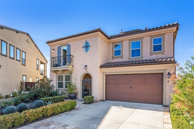 mediterranean / spanish-style home with stucco siding, an attached garage, a balcony, driveway, and a tiled roof