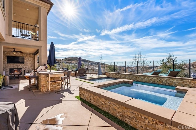 view of swimming pool with an in ground hot tub, exterior bar, exterior fireplace, and a patio