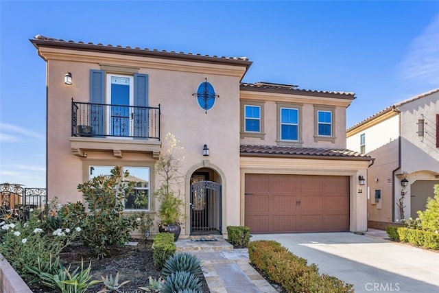 mediterranean / spanish-style house with a tile roof, stucco siding, concrete driveway, a balcony, and a garage