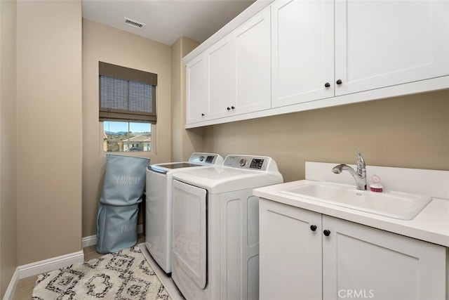 clothes washing area featuring cabinet space, visible vents, a sink, separate washer and dryer, and baseboards