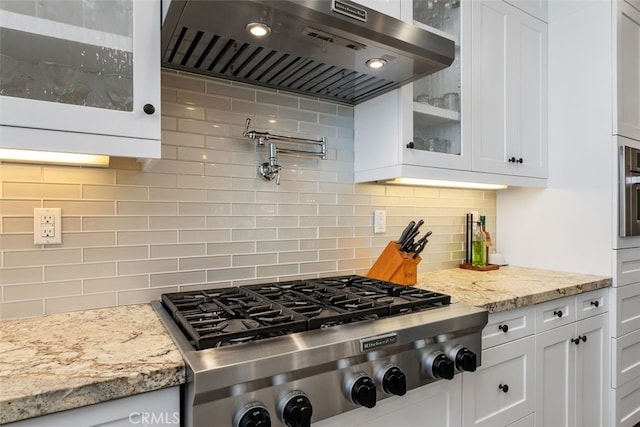 kitchen featuring white cabinets, stainless steel gas cooktop, backsplash, and wall chimney exhaust hood