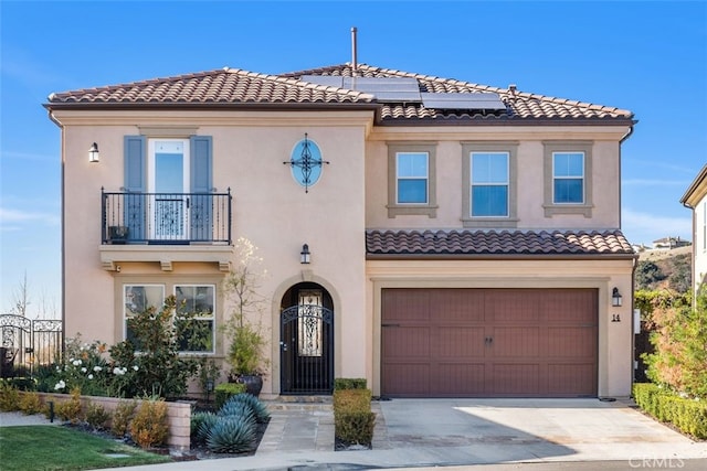 mediterranean / spanish-style house with driveway, solar panels, a balcony, a tiled roof, and stucco siding