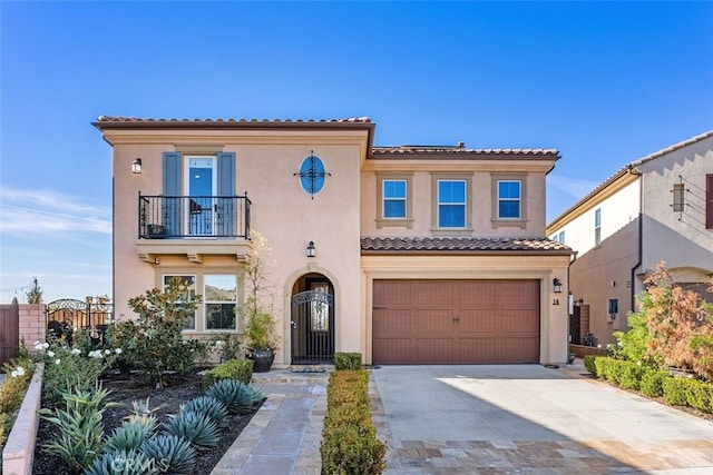 mediterranean / spanish-style house with a balcony, a garage, a tile roof, driveway, and stucco siding