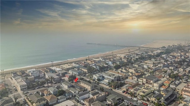 aerial view at dusk with a water view and a beach view