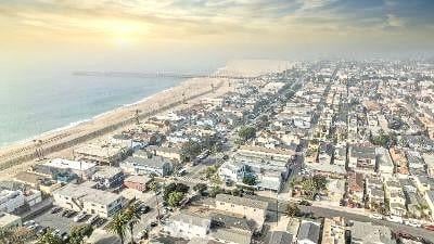 aerial view at dusk with a water view and a view of the beach