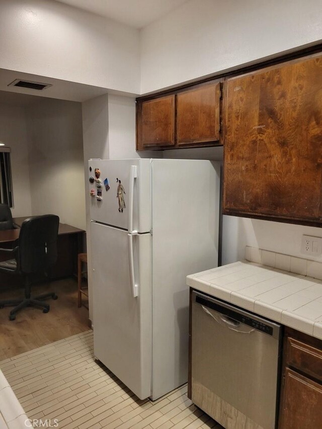 kitchen with white fridge, stainless steel dishwasher, and tile counters