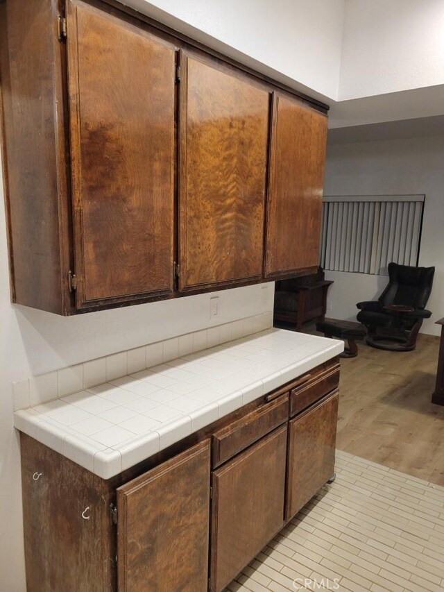 kitchen with tile countertops, dark brown cabinets, and light wood-type flooring