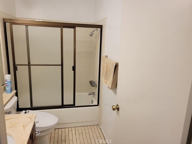 full bathroom featuring vanity, shower / bath combination with glass door, and toilet