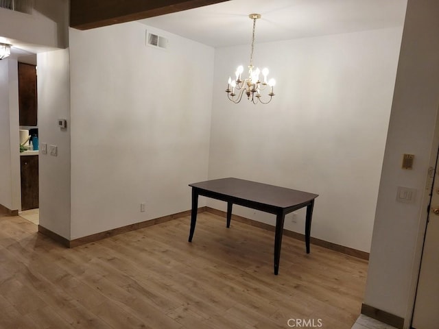 dining room with beamed ceiling, a notable chandelier, and light hardwood / wood-style flooring