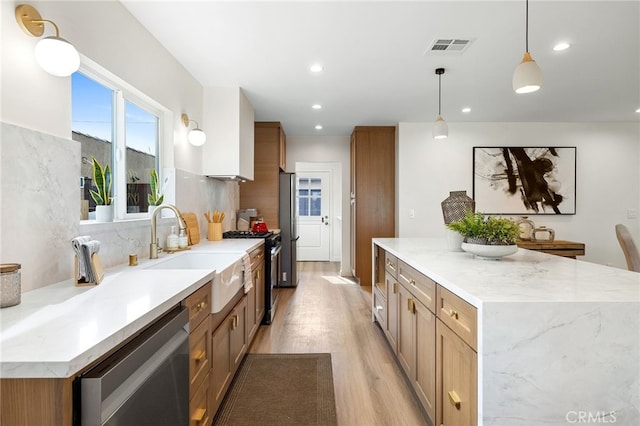 kitchen with sink, pendant lighting, stainless steel appliances, light stone countertops, and backsplash