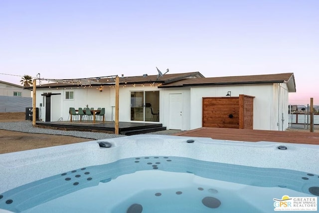 pool at dusk with a hot tub