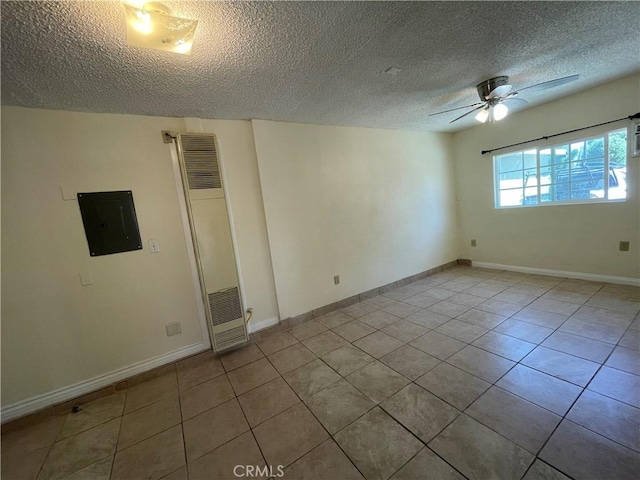 spare room with ceiling fan, electric panel, a textured ceiling, and light tile patterned flooring