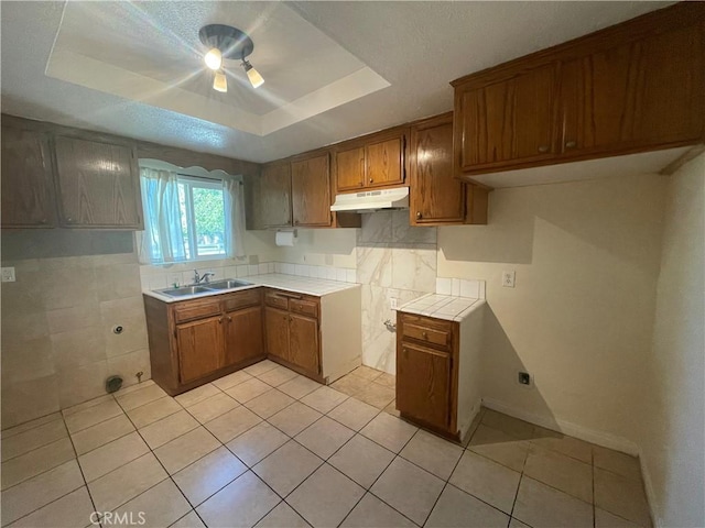 kitchen with sink, light tile patterned flooring, and a tray ceiling