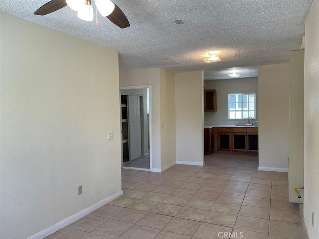 spare room featuring sink, light tile patterned floors, and ceiling fan