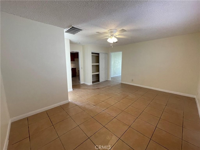 tiled spare room featuring a textured ceiling and ceiling fan